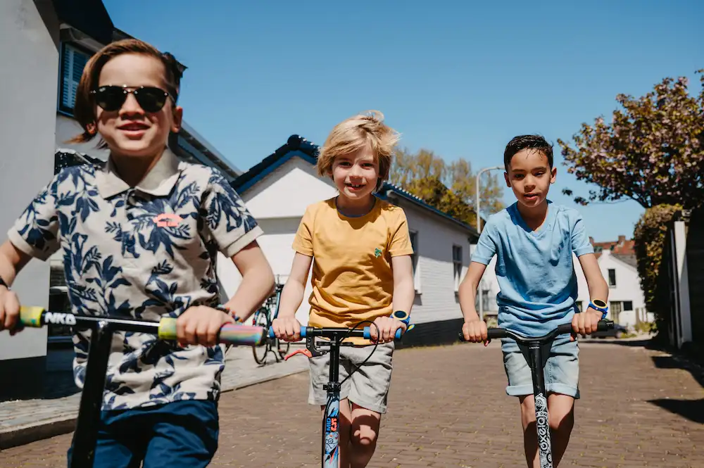 drie spelende kinderen op een step met een one2track gps-horloge