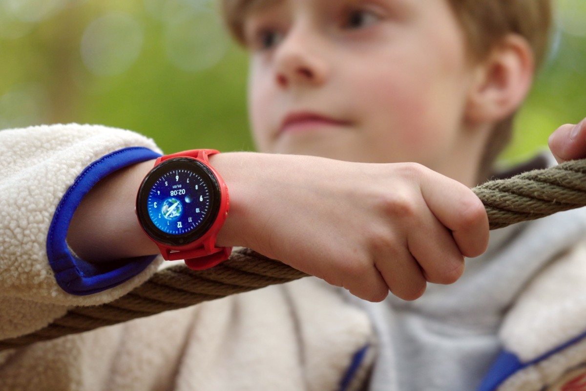 Kind met rood GPS horloge speelt buiten en houdt een touw vast